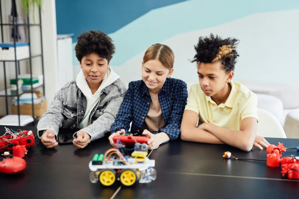 talleres educativos para adolescentes, cuatro adolescentes frente a una mesa, manejando un carro control remoto creado en su taller de robótica