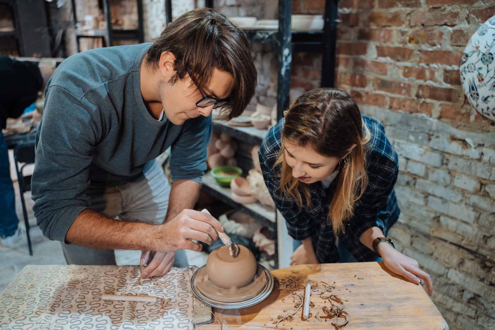 Talleres educativos para adolescentes trabajando con arcilla en un torno de alfarero. Haciendo una olla de barro artesanal. Clase de cerámica, afición.